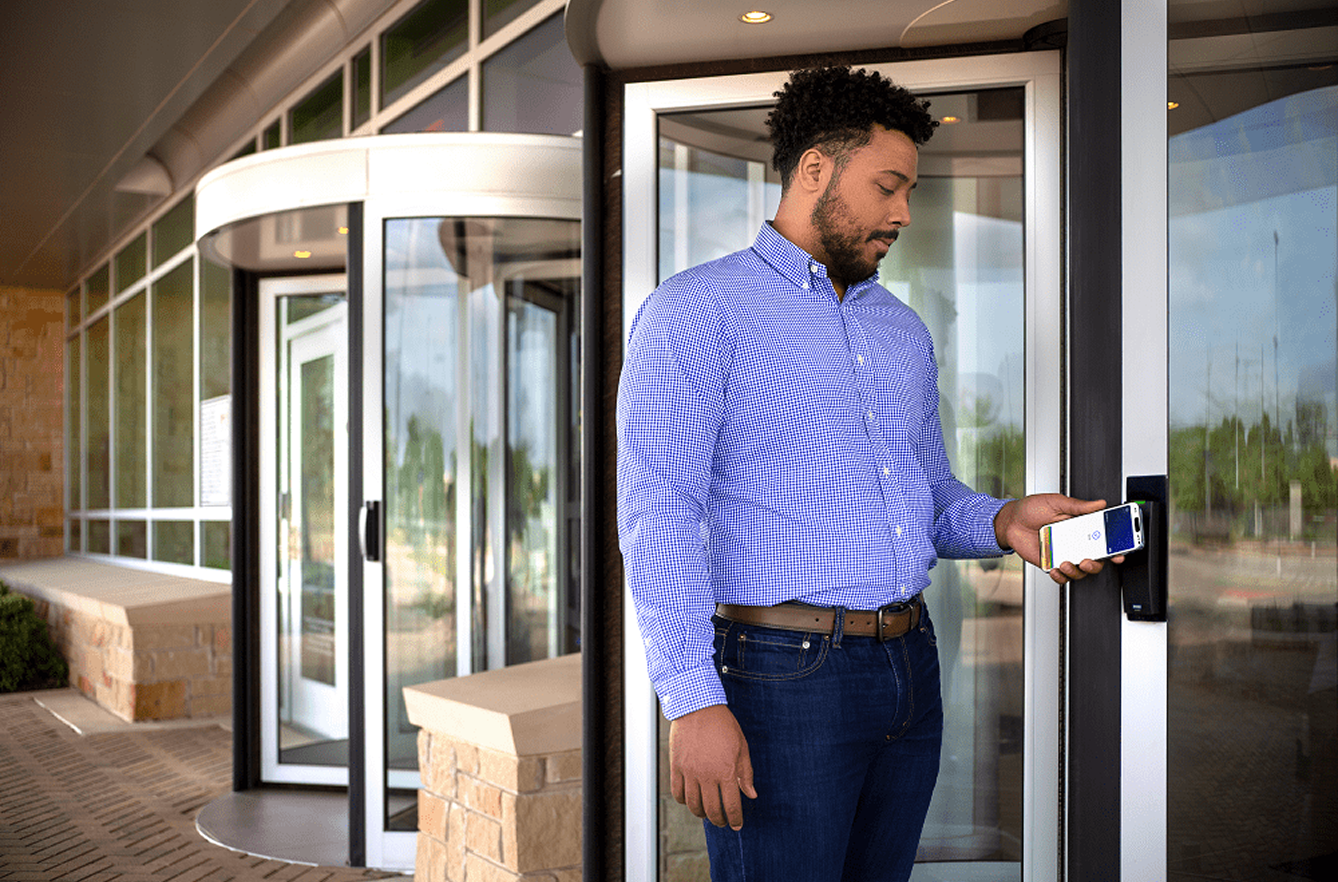 Man using smartphone to unlock office entrance with secure mobile access and encryption protection